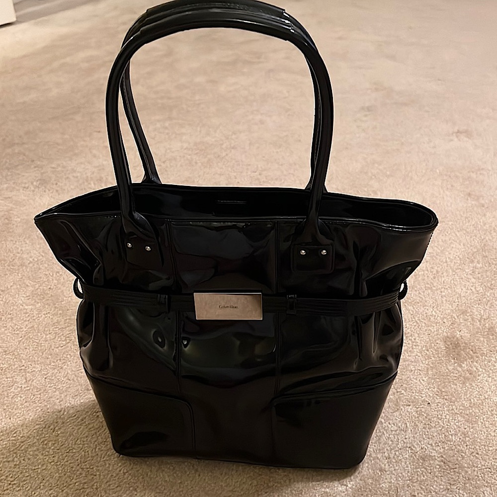 Calvin Klein patent leather bag that's accented with silver hardware.